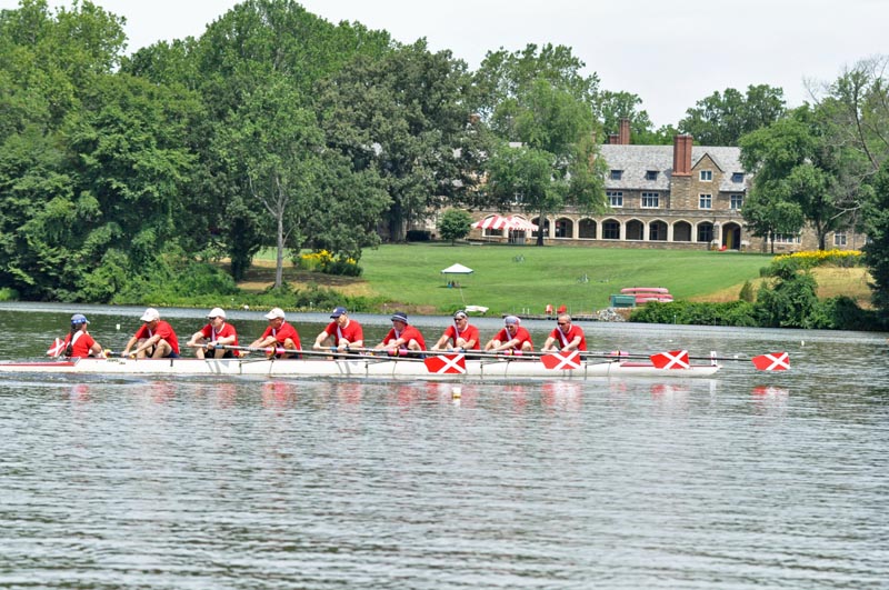 St Andrews School in the background, with an 8 with rowers in red shirts, and oars with the St. Andrews flag logo